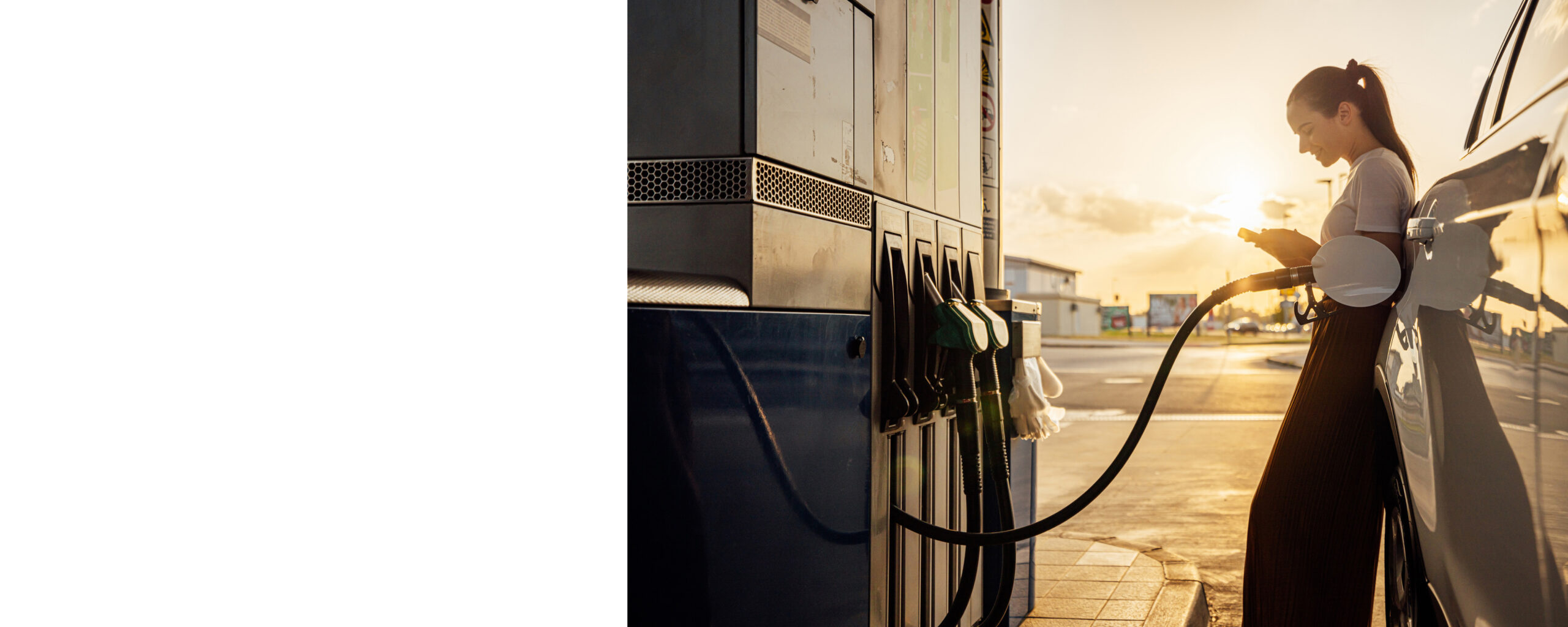 Young woman using mobile phone while refueling her car at gas station